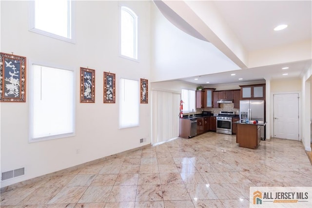 kitchen featuring visible vents, dark countertops, open floor plan, stainless steel appliances, and a wealth of natural light