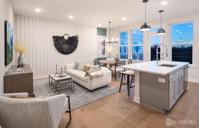 living area featuring light wood-style flooring, a notable chandelier, recessed lighting, and baseboards