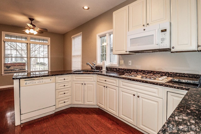 kitchen featuring ceiling fan, a peninsula, dark wood-style floors, white appliances, and a sink