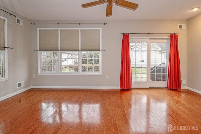 empty room with visible vents, ceiling fan, and hardwood / wood-style flooring