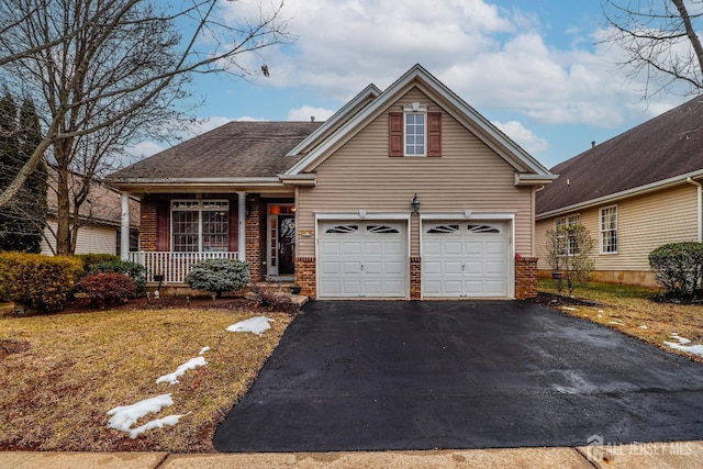 traditional-style home with aphalt driveway, an attached garage, brick siding, and covered porch