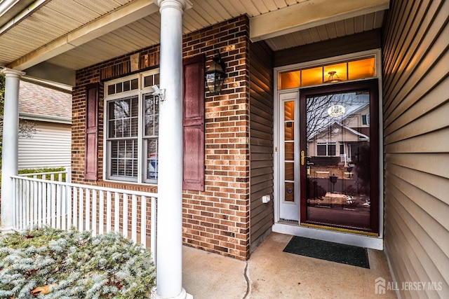 entrance to property with brick siding and a porch