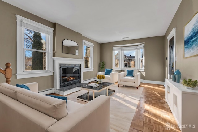 living room featuring a high end fireplace, light parquet flooring, and baseboard heating