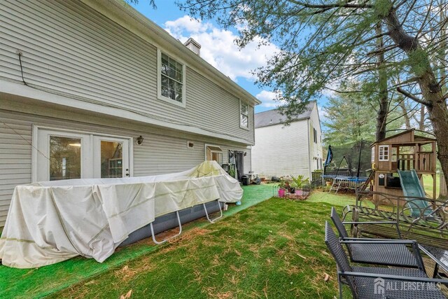 8 Carlisle Ct, Old Bridge, NJ 08857 - rear view of property with a trampoline, a lawn, a playground, and a chimney