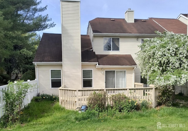 rear view of property with fence, a chimney, and a deck