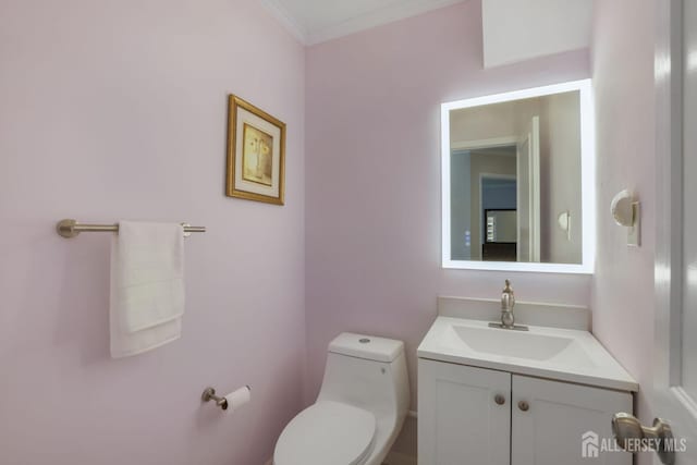 half bath featuring toilet, vanity, and ornamental molding