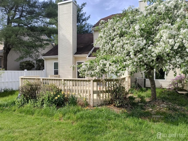 back of property with fence, roof with shingles, a chimney, and a wooden deck