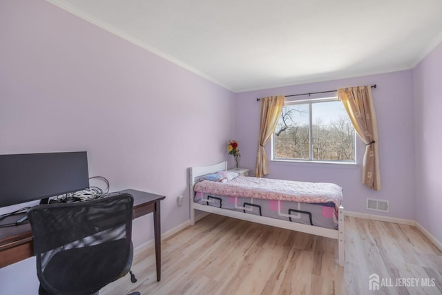 bedroom with baseboards, ornamental molding, light wood finished floors, and visible vents