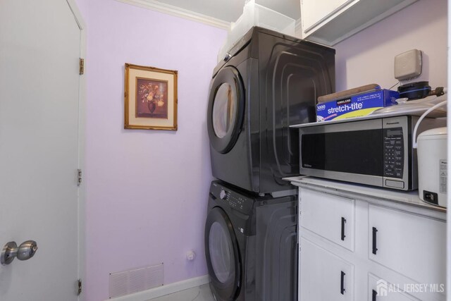laundry area with stacked washer / dryer, visible vents, and baseboards