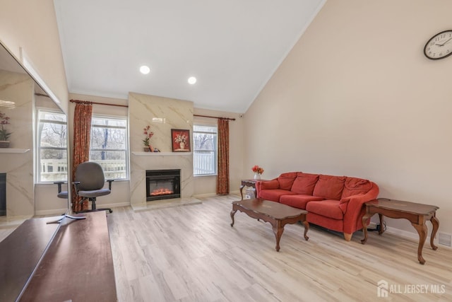 living room with recessed lighting, wood finished floors, baseboards, and a high end fireplace