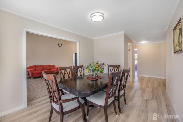 dining room with ornamental molding, light wood-style flooring, and baseboards