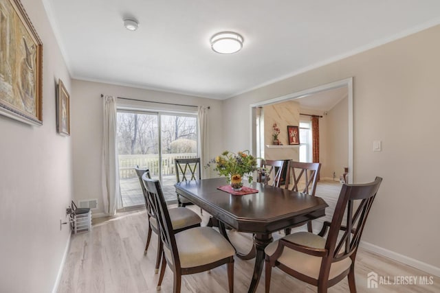 dining area with light wood-type flooring, visible vents, baseboards, and ornamental molding
