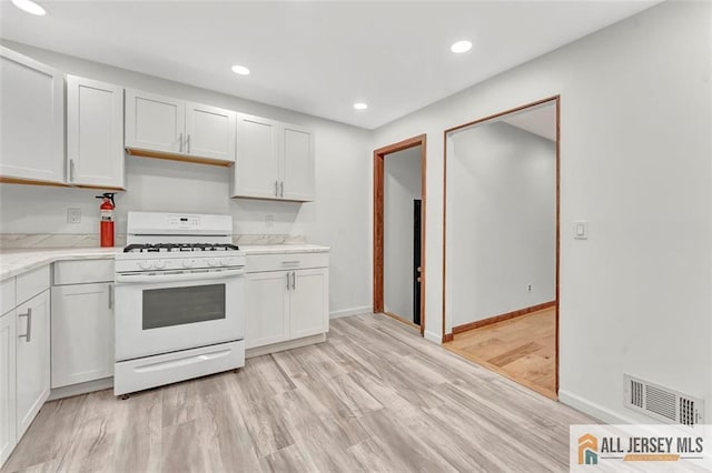 440 E Ave, Sewaren, NJ 07077 - kitchen with white range with gas cooktop, light wood-style flooring, recessed lighting, white cabinetry, and light stone counters