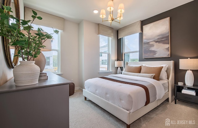 bedroom featuring a notable chandelier, multiple windows, and light colored carpet