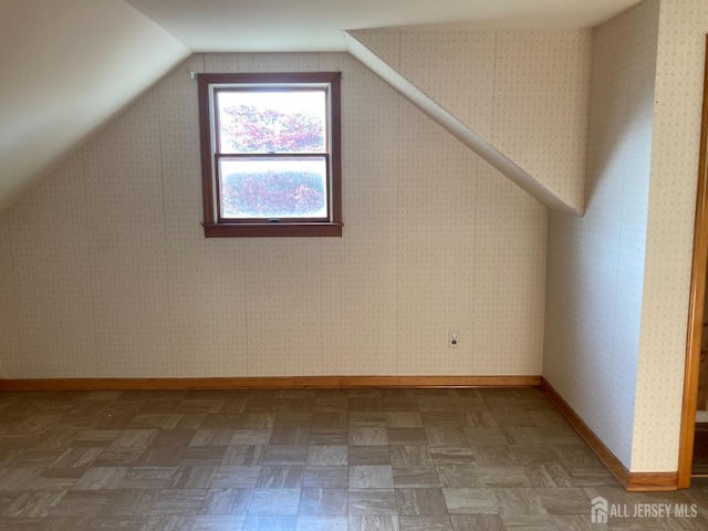 additional living space with baseboards and vaulted ceiling