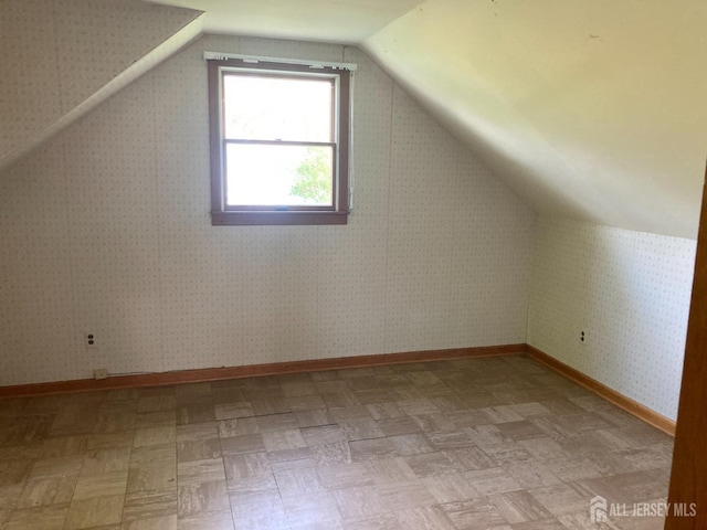 bonus room with baseboards and lofted ceiling