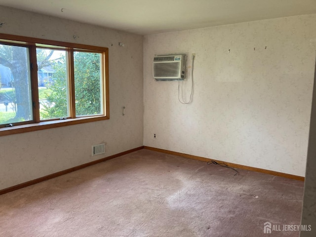 carpeted spare room featuring visible vents, a wall mounted air conditioner, and baseboards