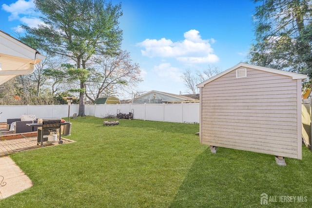 view of yard featuring an outbuilding, a fenced backyard, a fire pit, and a shed