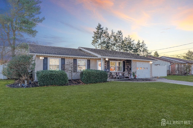 single story home featuring a garage, driveway, and a yard