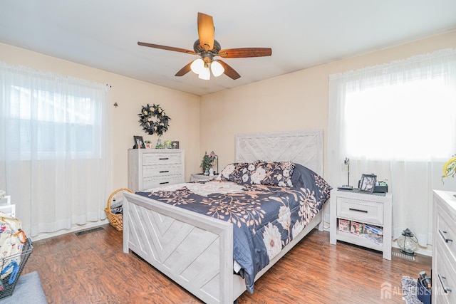 bedroom with ceiling fan, visible vents, and dark wood-type flooring