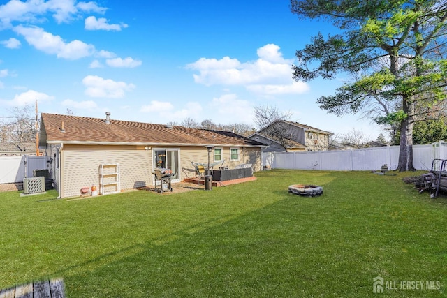 back of property featuring a fenced backyard, a yard, and a fire pit