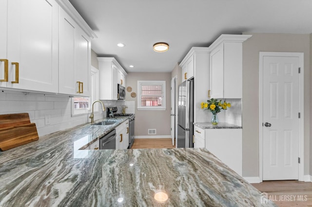 226 Schussler St, Sayreville, NJ 08879 - kitchen featuring appliances with stainless steel finishes, light stone countertops, white cabinets, tasteful backsplash, and recessed lighting