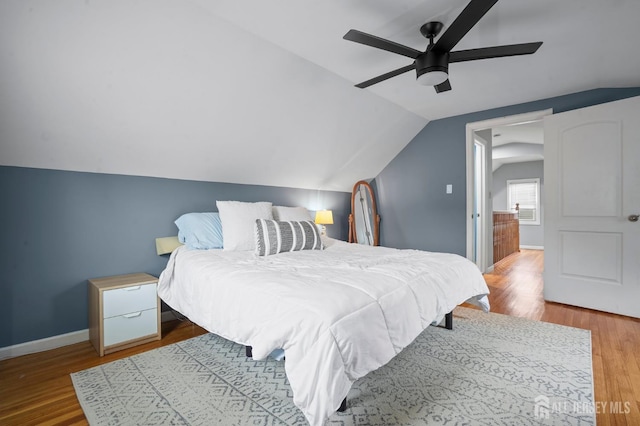 bedroom with vaulted ceiling, wood finished floors, a ceiling fan, and baseboards