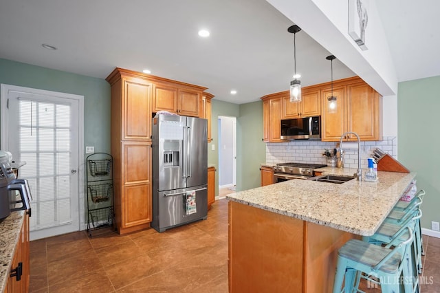 kitchen with high quality appliances, a sink, a peninsula, light stone countertops, and tasteful backsplash