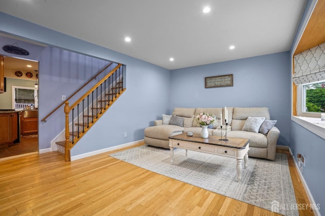 living room with light wood-type flooring, stairs, baseboards, and recessed lighting