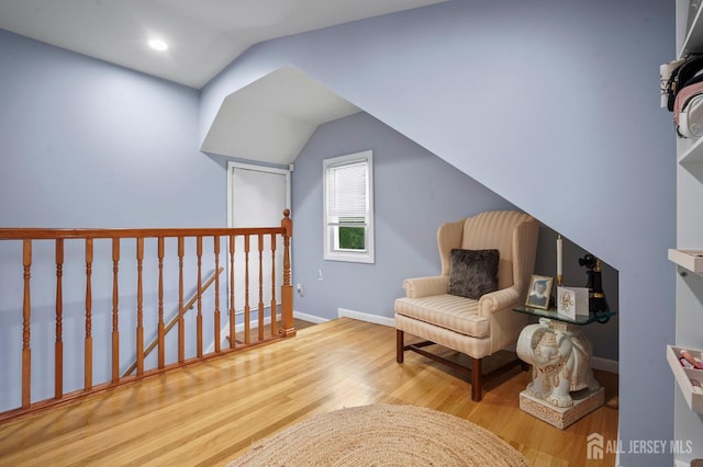 living area featuring an upstairs landing, vaulted ceiling, wood finished floors, and baseboards