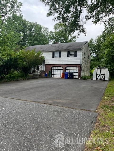 1436 Thomas Ave, North Brunswick, NJ 08902 - view of front of property featuring a garage, brick siding, and asphalt driveway
