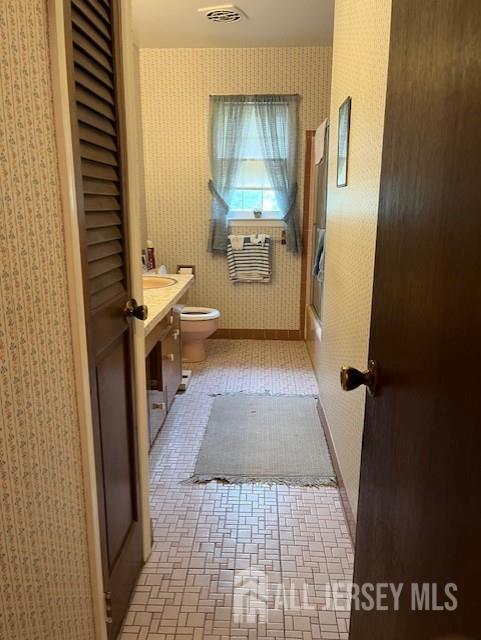 1436 Thomas Ave, North Brunswick, NJ 08902 - bathroom with vanity, wallpapered walls, toilet, and brick patterned flooring