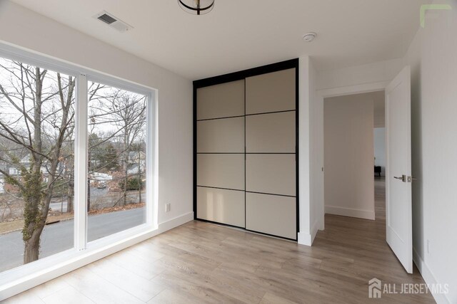 unfurnished bedroom with baseboards, visible vents, and light wood-style floors