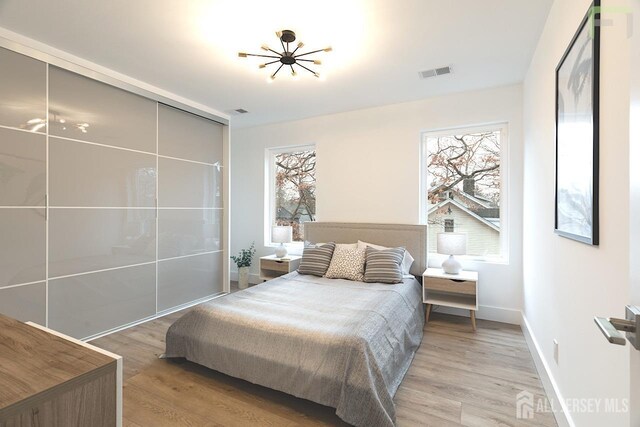 bedroom featuring light wood finished floors, baseboards, and visible vents