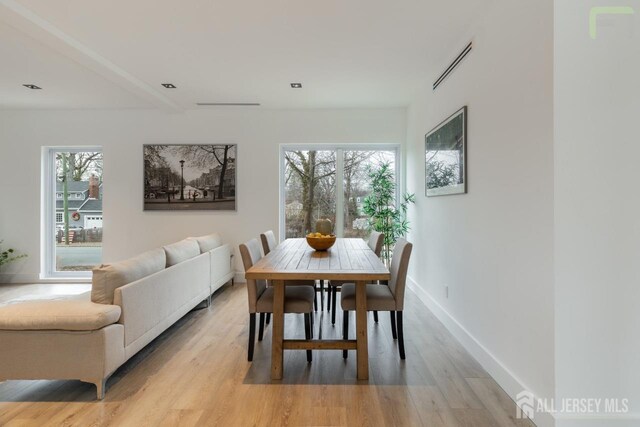 dining area with light wood-type flooring, visible vents, and baseboards