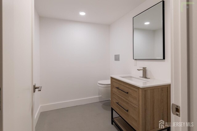 bathroom featuring recessed lighting, toilet, finished concrete floors, vanity, and baseboards