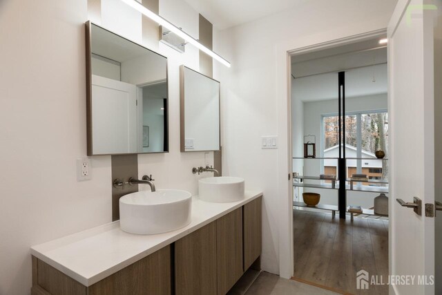 full bathroom with wood finished floors, a sink, and double vanity