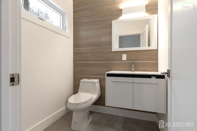 bathroom featuring toilet, wood walls, tile patterned flooring, and vanity