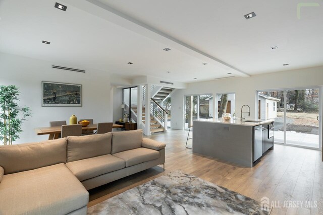 living area featuring light wood-type flooring, a healthy amount of sunlight, and stairway