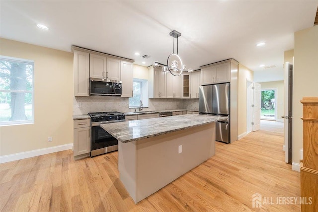 17 Fourth St, Hillsborough, NJ 08821 - kitchen featuring stainless steel appliances, a kitchen island, a chandelier, light stone counters, and tasteful backsplash