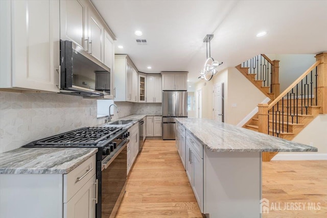 17 Fourth St, Hillsborough, NJ 08821 - kitchen featuring appliances with stainless steel finishes, light wood-type flooring, a sink, a kitchen island, and light stone countertops