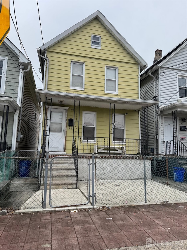 view of front of house featuring a porch, a fenced front yard, and a gate