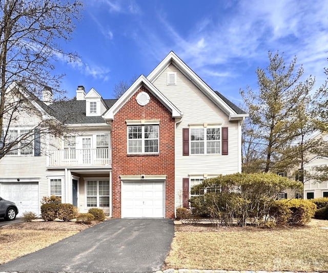 view of front of house with a balcony, brick siding, a garage, and driveway