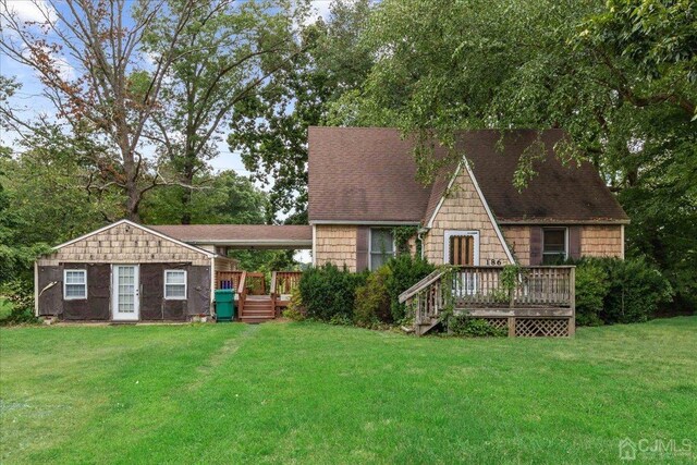 rear view of property with a yard, an outdoor structure, and a wooden deck