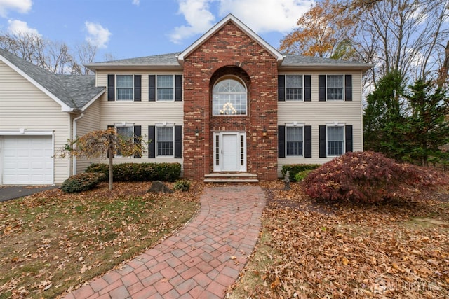 colonial home with brick siding, driveway, and an attached garage