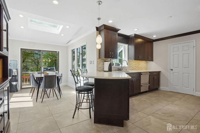 4 Franklin Ct, East Brunswick, NJ 08816 - kitchen with a skylight, light countertops, dark brown cabinetry, ornamental molding, and backsplash