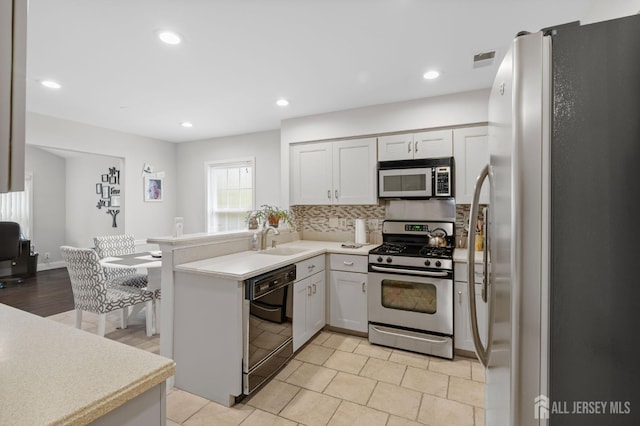 31 Ingram Dr, Monroe, NJ 08831 - kitchen featuring appliances with stainless steel finishes, a peninsula, light countertops, tasteful backsplash, and recessed lighting