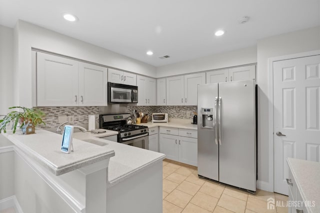 31 Ingram Dr, Monroe, NJ 08831 - kitchen featuring appliances with stainless steel finishes, decorative backsplash, light countertops, a peninsula, and light tile patterned flooring