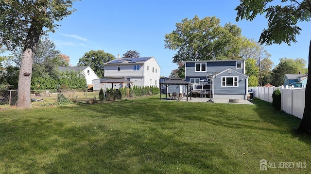 back of property with a gazebo, a fenced backyard, a patio, and a yard