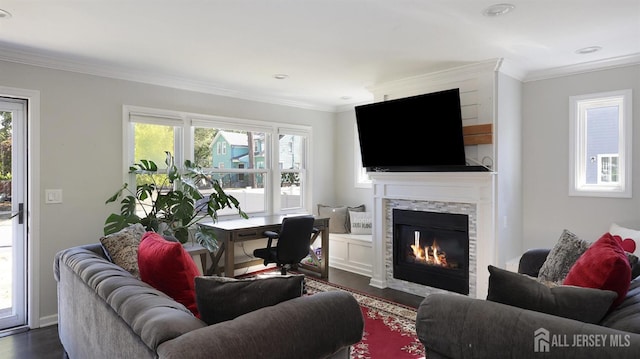 living area featuring a glass covered fireplace, dark wood-style floors, and crown molding